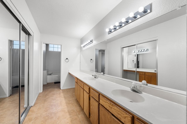 bathroom featuring vanity, tile patterned flooring, a washtub, and a textured ceiling