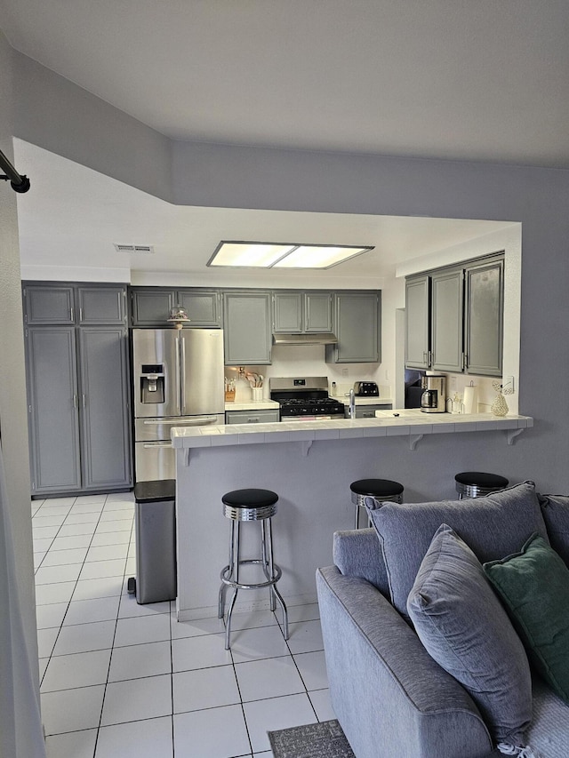 403 Sunrise Ter, Palmdale, CA 93551 - kitchen featuring tile counters, a kitchen breakfast bar, stainless steel appliances, open floor plan, and light tile patterned floors