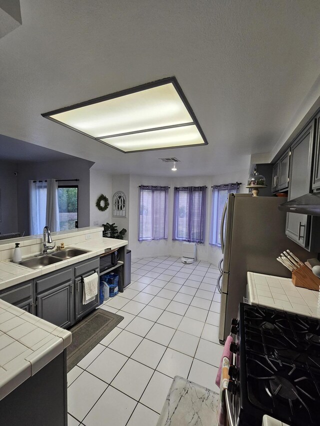 403 Sunrise Ter, Palmdale, CA 93551 - kitchen featuring stainless steel gas range, light tile patterned flooring, a sink, tile countertops, and visible vents
