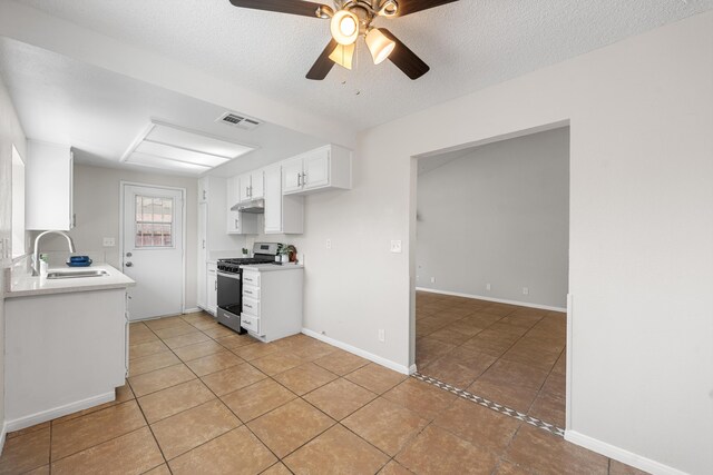38115 E 41st St, Palmdale, CA 93552 - kitchen featuring stainless steel gas range oven, a sink, light tile patterned floors, under cabinet range hood, and a textured ceiling