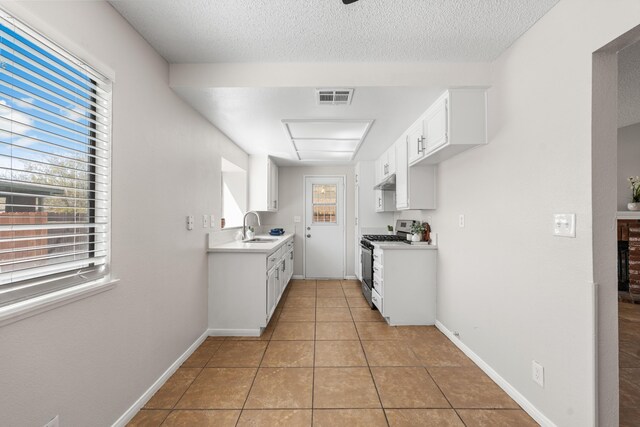 38115 E 41st St, Palmdale, CA 93552 - kitchen featuring stainless steel range with gas cooktop, a sink, under cabinet range hood, light countertops, and white cabinetry