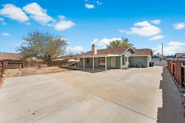 38115 E 41st St, Palmdale, CA 93552 - rear view of house featuring a fenced backyard, a patio, a chimney, concrete driveway, and stucco siding
