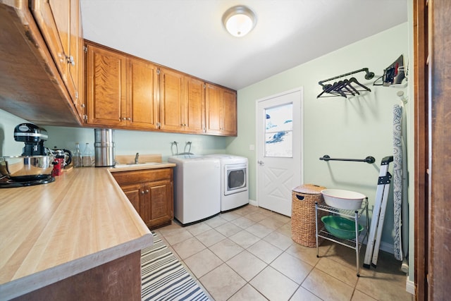 washroom featuring separate washer and dryer, sink, light tile patterned floors, and cabinets