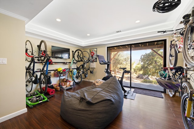 exercise area with hardwood / wood-style flooring, ornamental molding, and a tray ceiling