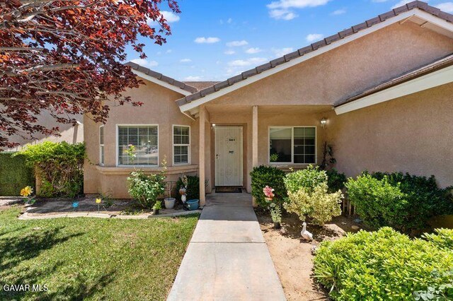 43656 E 5th St, Lancaster, CA 93535 - doorway to property featuring stucco siding and a lawn