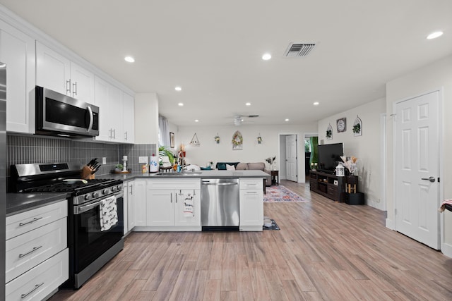 kitchen with visible vents, dark countertops, open floor plan, a peninsula, and stainless steel appliances