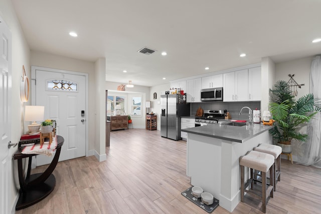 kitchen featuring visible vents, appliances with stainless steel finishes, light wood-type flooring, white cabinetry, and a sink