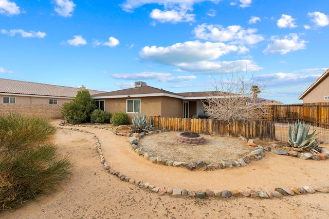 exterior space with an outdoor fire pit, fence, and stucco siding