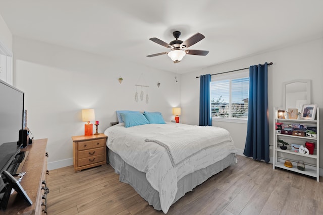 bedroom featuring a ceiling fan, light wood-style flooring, and baseboards