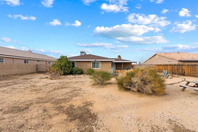 rear view of house featuring a fenced backyard and stucco siding