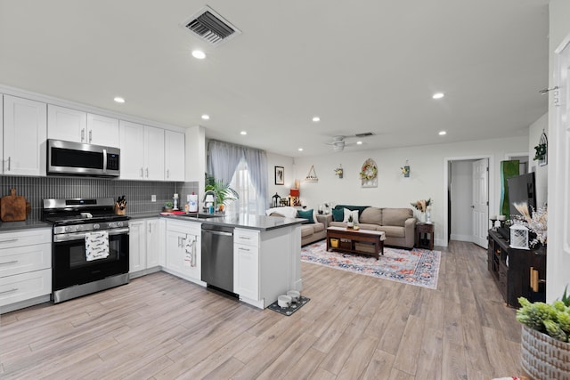 kitchen with a peninsula, a sink, visible vents, open floor plan, and appliances with stainless steel finishes