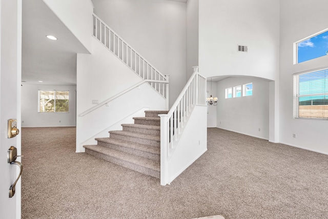 stairway featuring carpet, a chandelier, and a high ceiling