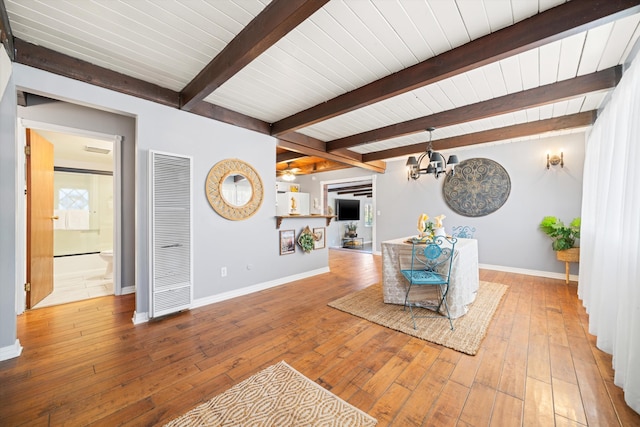 unfurnished living room featuring beam ceiling, hardwood / wood-style floors, and an inviting chandelier