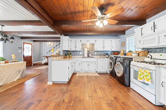 kitchen with washing machine and clothes dryer, sink, backsplash, white appliances, and white cabinets