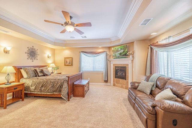 bedroom featuring a tray ceiling, multiple windows, ceiling fan, and light colored carpet