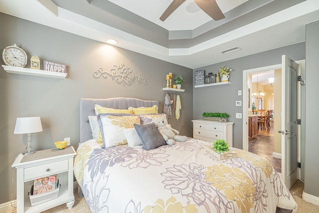 bedroom with carpet floors, a raised ceiling, and ceiling fan