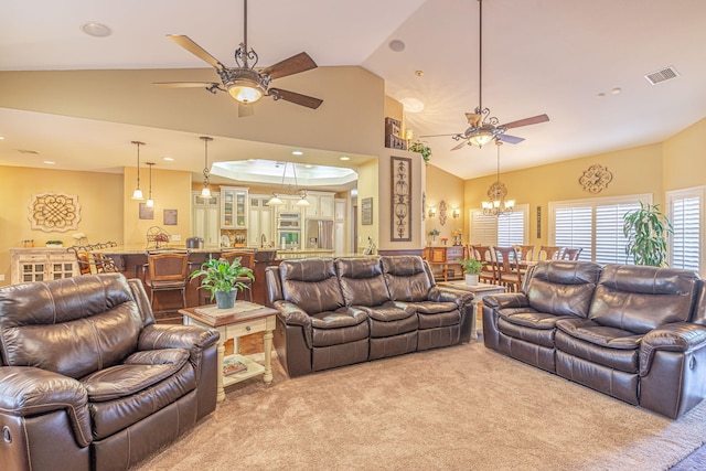 carpeted living room featuring ceiling fan with notable chandelier and vaulted ceiling