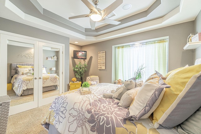 bedroom featuring a raised ceiling, ceiling fan, french doors, and carpet flooring