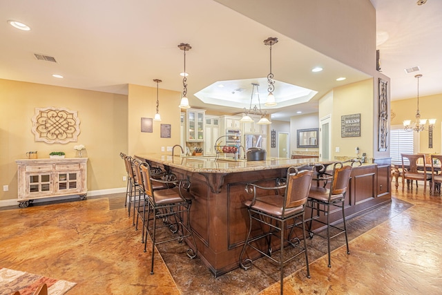 bar with pendant lighting, an inviting chandelier, a raised ceiling, and sink