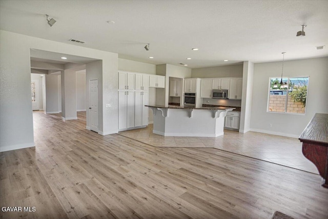 41729 Firenze St, Lancaster, CA 93536 - kitchen featuring appliances with stainless steel finishes, white cabinetry, a kitchen breakfast bar, dark countertops, and recessed lighting