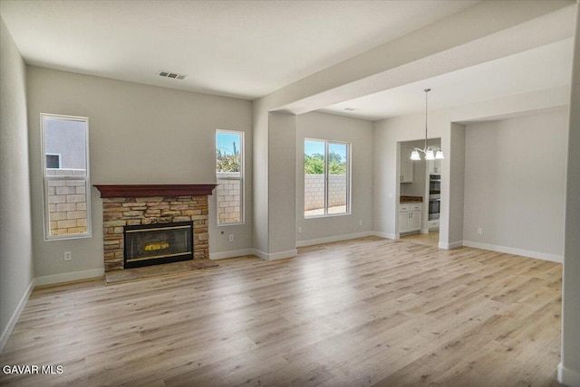 41729 Firenze St, Lancaster, CA 93536 - unfurnished living room featuring a chandelier, a stone fireplace, and light wood finished floors