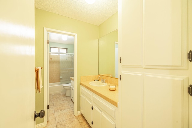 full bath with a textured ceiling, vanity, bath / shower combo with glass door, tile patterned floors, and toilet