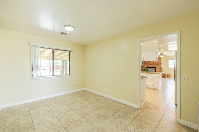 unfurnished room featuring a healthy amount of sunlight, baseboards, light tile patterned flooring, and visible vents