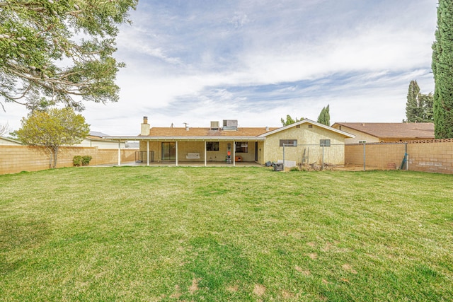 rear view of property with a lawn, a fenced backyard, and a patio area
