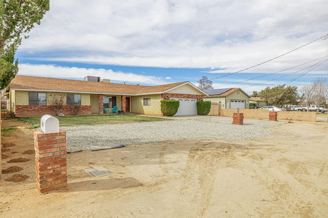 ranch-style house featuring a garage, fence, driveway, and brick siding