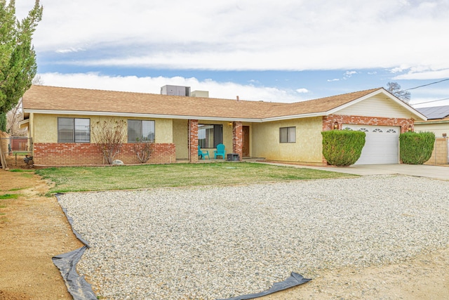 single story home featuring a front yard, stucco siding, brick siding, concrete driveway, and an attached garage