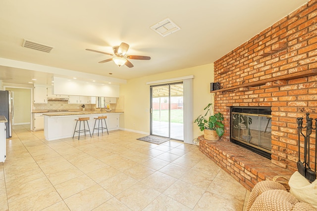 living area with ceiling fan, visible vents, light tile patterned floors, and a fireplace