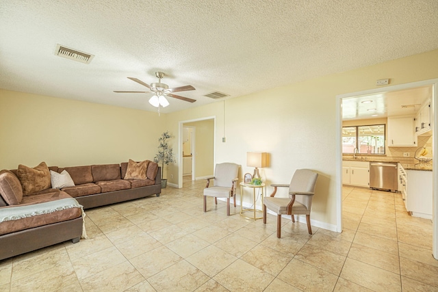 living area with visible vents, a ceiling fan, a textured ceiling, and baseboards