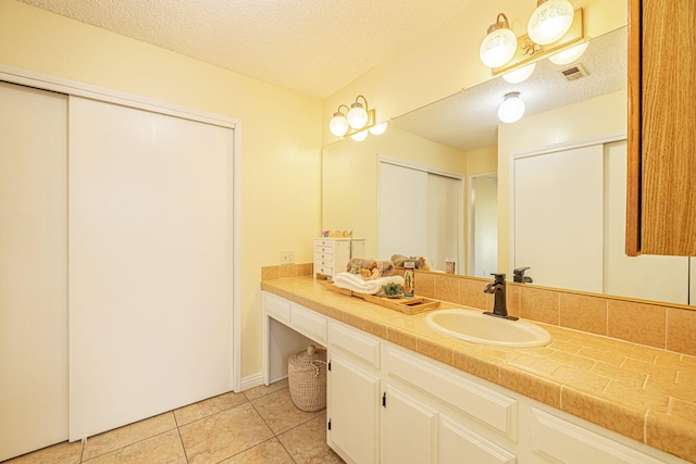 bathroom with vanity, a textured ceiling, tile patterned floors, and visible vents