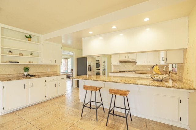 kitchen with open shelves, gas cooktop, a peninsula, decorative backsplash, and under cabinet range hood