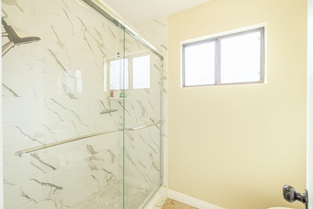 full bathroom featuring a marble finish shower and baseboards