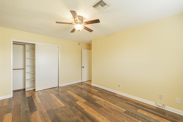 unfurnished bedroom with ceiling fan, a textured ceiling, visible vents, baseboards, and dark wood-style floors