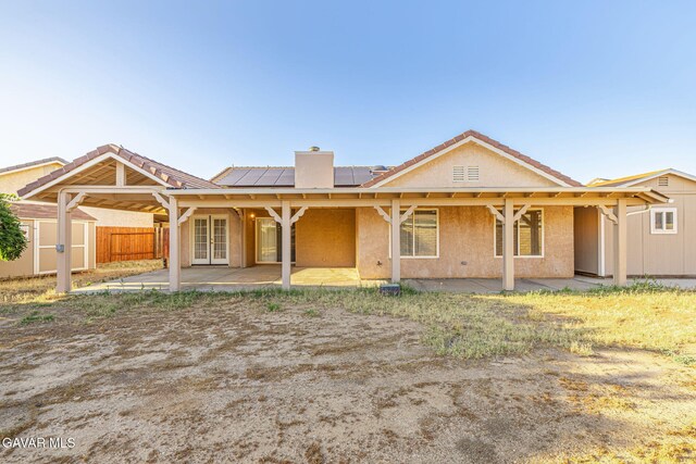 4068 Vancouver Ln, Quartz Hill, CA 93536 - rear view of property featuring a patio area, a storage unit, a chimney, roof mounted solar panels, and french doors