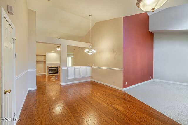 4068 Vancouver Ln, Quartz Hill, CA 93536 - unfurnished living room featuring vaulted ceiling, a chandelier, wood-type flooring, a glass covered fireplace, and a ceiling fan