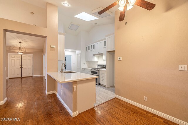 4068 Vancouver Ln, Quartz Hill, CA 93536 - kitchen featuring range with two ovens, a peninsula, a ceiling fan, light wood-type flooring, and a skylight