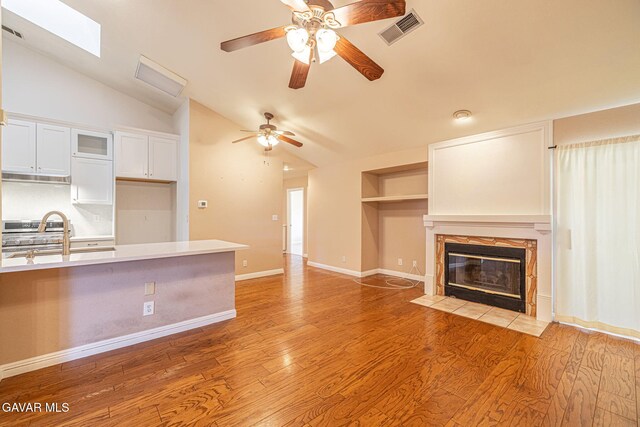 4068 Vancouver Ln, Quartz Hill, CA 93536 - unfurnished living room with vaulted ceiling, ceiling fan, light wood-style floors, a fireplace, and built in features