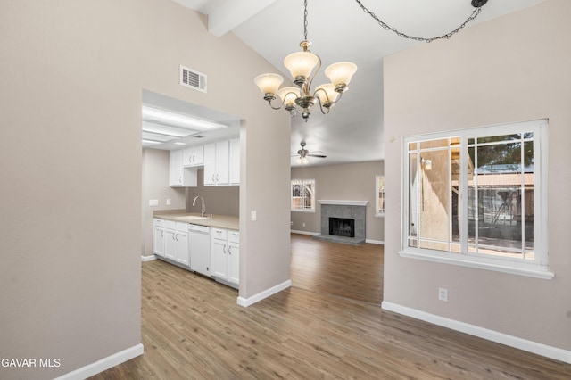 4633 Dowel Ave, Palmdale, CA 93552 - kitchen featuring dishwasher, beamed ceiling, a fireplace with raised hearth, high vaulted ceiling, and white cabinetry