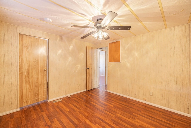 unfurnished room featuring ceiling fan, hardwood / wood-style floors, and wood walls