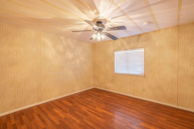 unfurnished room with hardwood / wood-style floors, ceiling fan, and wood walls