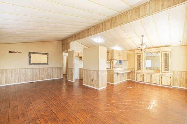 unfurnished living room featuring a chandelier, dark hardwood / wood-style flooring, and vaulted ceiling