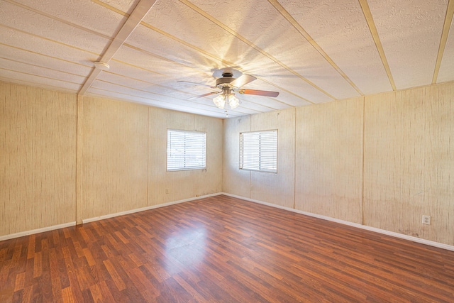 spare room with dark hardwood / wood-style flooring, ceiling fan, and wood walls