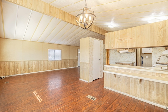 kitchen featuring an inviting chandelier, sink, vaulted ceiling, decorative light fixtures, and dark hardwood / wood-style flooring