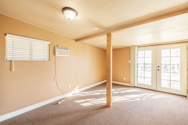 carpeted empty room with beam ceiling, an AC wall unit, a textured ceiling, and french doors