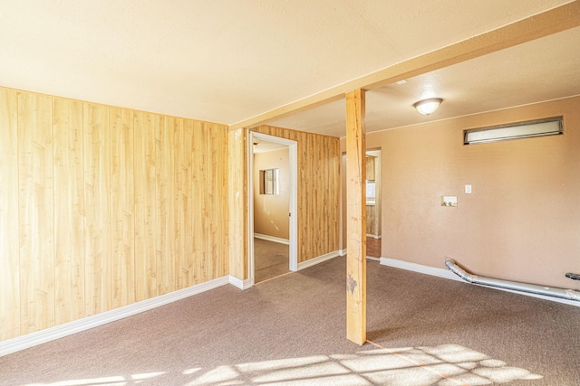 unfurnished room featuring carpet and wood walls