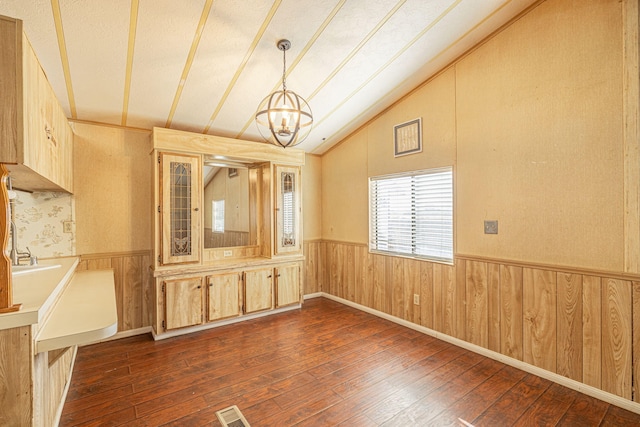 unfurnished room featuring dark hardwood / wood-style flooring, vaulted ceiling, and a notable chandelier