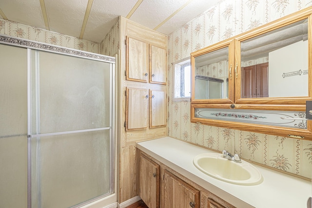 bathroom featuring a textured ceiling, vanity, and an enclosed shower